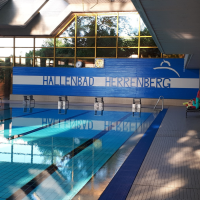 Innenansicht des Hallenbads Herrenberg mit einem Schwimmbecken, Startblöcken und großen Fenstern, die viel Licht hereinlassen., © Stadtwerke Herrenberg