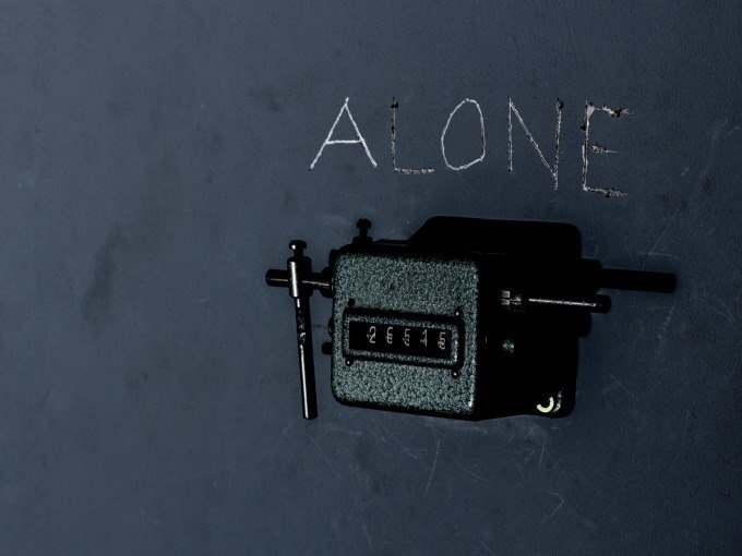 Ein mechanischer Z&auml;hler an einer dunklen Wand, dar&uuml;ber steht das Wort 'ALONE' in Kreide geschrieben., &copy; ExitGames Stuttgart