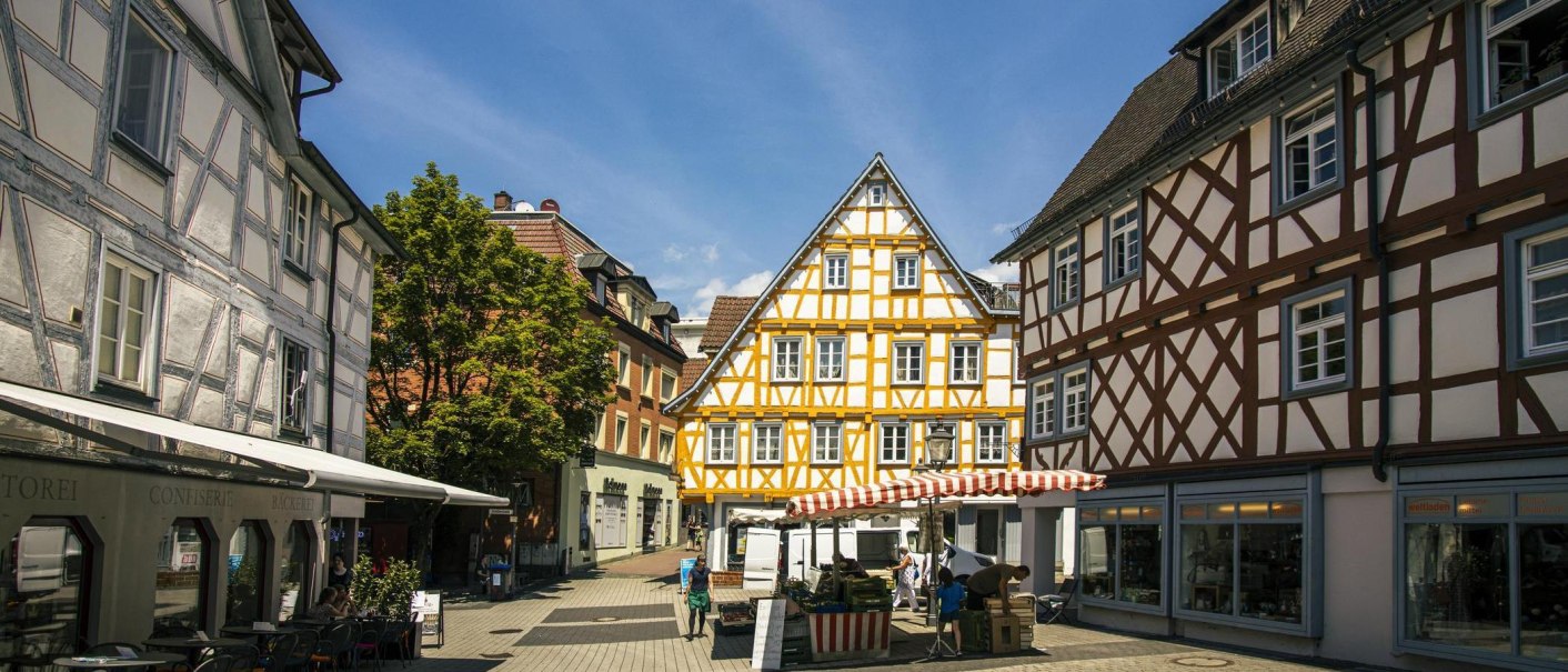 Fachwerkhäuser in der Altstadt von Backnang, umgeben von Marktständen und Passanten bei sonnigem Wetter., © Stuttgart-Marketing GmbH, Sarah Schmid