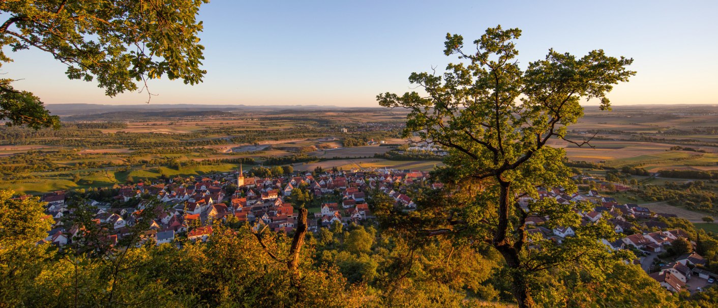 Blick auf ein Dorf im Heckengäu, umgeben von Feldern und Bäumen. Die Abendsonne taucht die Landschaft in warmes Licht., © Stuttgart-Marketing GmbH, Achim Mende