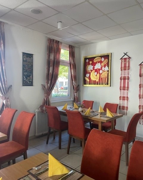 Ein gemütliches Restaurant mit roten Stühlen, gelben Servietten und asiatischer Dekoration an den Wänden., © cKabkao Ein gemütliches Restaurant mit roten Stühlen, gelben Servietten und asiatischer Dekoration an den Wänden., © cKabkao