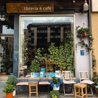 Ein gemütliches Außencafé mit Pflanzen, Büchern im Fenster und mehreren Stühlen vor der Fassade., © Café Che