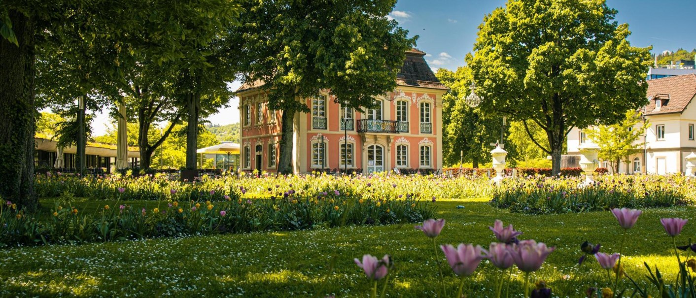 Ein elegantes, rosa Gebäude im Stadtpark von Schwäbisch Gmünd, umgeben von blühenden Blumen und grünen Bäumen an einem sonnigen Tag., © Stuttgart-Marketing GmbH, Sarah Schmid