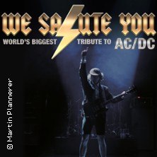 Poster einer Tribute-Band mit Gitarrist im Rampenlicht. Text: "WE SALUTE YOU - World's Biggest Tribute to AC/DC"., © links im Bild