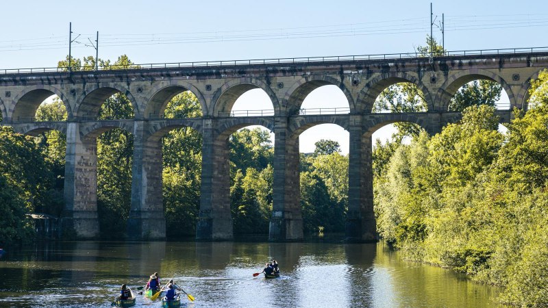 Viadukt in Bietigheim-Bissingen über einem Fluss. Mehrere Kanufahrer paddeln unter der Brücke. Umgeben von grünen Bäumen und klarem Himmel., © Stuttgart Marketing GmbH, Sarah Schmid