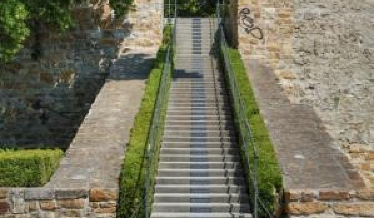 Eine steile Steintreppe führt zu einer alten Mauer, flankiert von Bäumen und Sträuchern. Der Himmel ist klar und blau., © Stadt Kirchheim unter Teck Eine steile Steintreppe führt zu einer alten Mauer, flankiert von Bäumen und Sträuchern. Der Himmel ist klar und blau., © Stadt Kirchheim unter Teck