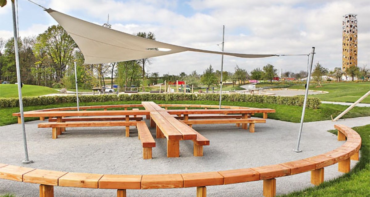 Großer Park, in der Mitte steht ein Tisch aus Holz in Form von einem Kreuz, um den Tisch herum ist eine runde Holzbank. Über den Tisch ist ein weißes Sonnensegel gespannt. Im Hintergrund sieht man einen Hohen Aussichtsturm - den Himmelsstürmer., © Schönblick - Christliches Gästezentrum Württemberg Großer Park, in der Mitte steht ein Tisch aus Holz in Form von einem Kreuz, um den Tisch herum ist eine runde Holzbank. Über den Tisch ist ein weißes Sonnensegel gespannt. Im Hintergrund sieht man einen Hohen Aussichtsturm - den Himmelsstürmer., © Schönblick - Christliches Gästezentrum Württemberg