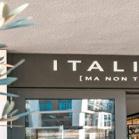 Eingang eines Restaurants mit dem Schild 'ITALIANI [MA NON TROPPO]'. Im Vordergrund sind unscharfe Pflanzen zu sehen., © SMG Stuttgart Marketing GmbH - Sarah Schmid