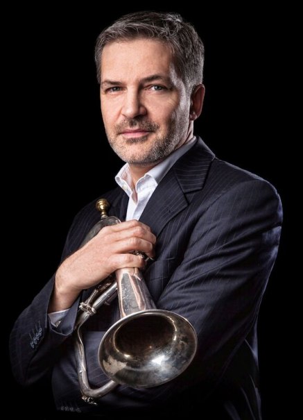 Ein Mann im Anzug h&auml;lt eine Trompete und blickt selbstbewusst in die Kamera. Der Hintergrund ist schwarz, was den Fokus auf die Person lenkt., &copy; Stadt B&ouml;blingen - Amt f&uuml;r Kultur