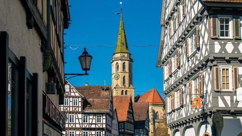 Fachwerkhäuser in der Altstadt von Schorndorf, mit einem Kirchturm im Hintergrund unter klarem, blauem Himmel., © Stuttgart-Marketing GmbH, Sarah Schmid Fachwerkhäuser in der Altstadt von Schorndorf, mit einem Kirchturm im Hintergrund unter klarem, blauem Himmel., © Stuttgart-Marketing GmbH, Sarah Schmid
