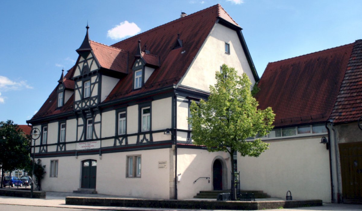 Fachwerkhaus mit rotem Satteldach und dekorativen Giebeln. Ein Baum steht im Vordergrund, der Himmel ist blau mit wenigen Wolken., © Nürtingen - Stuttgart-Marketing GmbH Fachwerkhaus mit rotem Satteldach und dekorativen Giebeln. Ein Baum steht im Vordergrund, der Himmel ist blau mit wenigen Wolken., © Nürtingen - Stuttgart-Marketing GmbH
