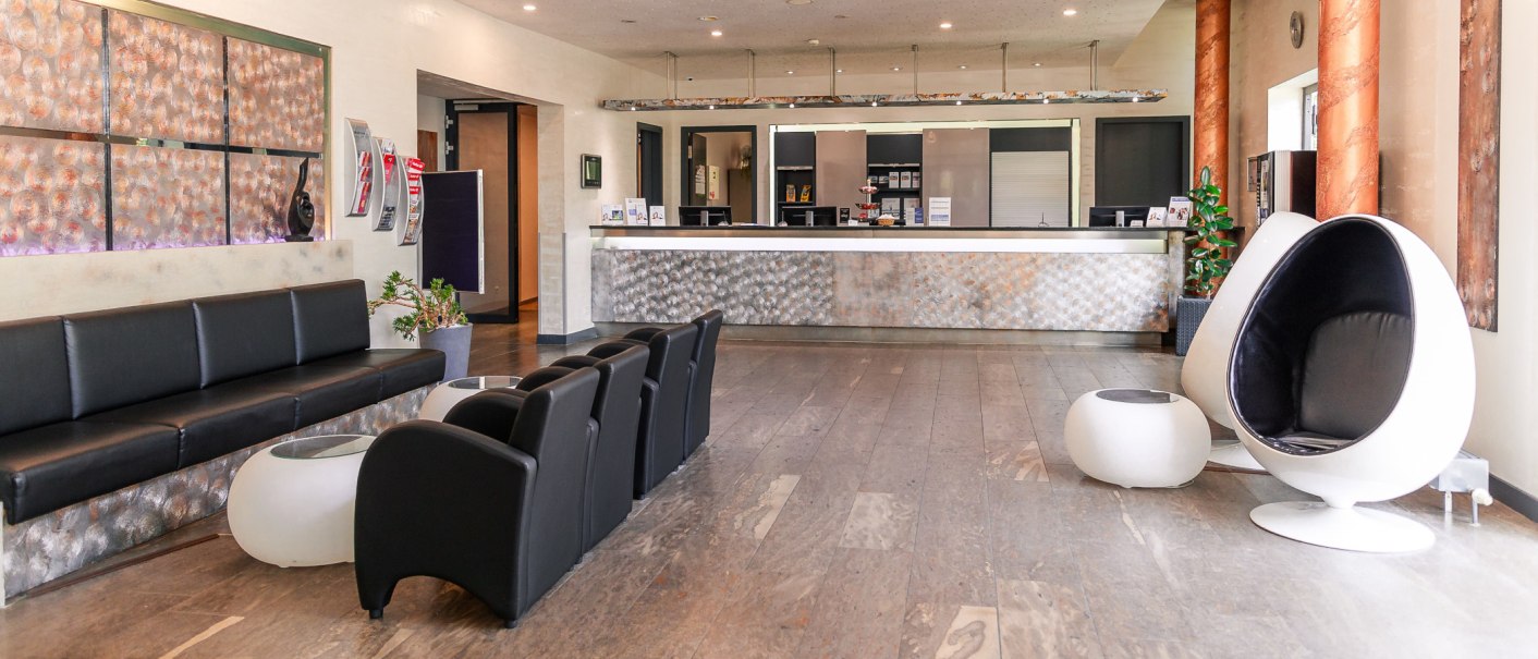 Moderne Lobby mit schwarzen Sofas, weißen Designerstühlen und einer Rezeption. Dekorative Wände und Pflanzen schaffen eine einladende Atmosphäre., © PLAZA Hotelgroup GmbH Moderne Lobby mit schwarzen Sofas, weißen Designerstühlen und einer Rezeption. Dekorative Wände und Pflanzen schaffen eine einladende Atmosphäre., © PLAZA Hotelgroup GmbH