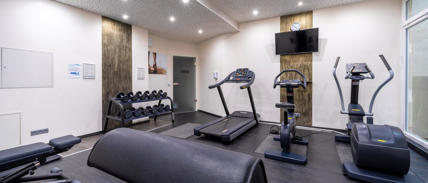 Moderner Fitnessraum mit Laufband, Crosstrainer, Hantelbank und Gewichten. Helle Beleuchtung und ein Fernseher an der Wand., © Plaza Residence Stuttgart-Ditzingen Moderner Fitnessraum mit Laufband, Crosstrainer, Hantelbank und Gewichten. Helle Beleuchtung und ein Fernseher an der Wand., © Plaza Residence Stuttgart-Ditzingen