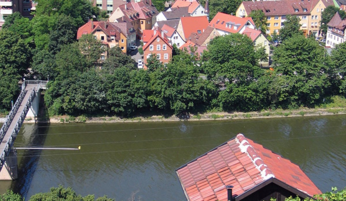 Blick auf den Neckar mit einer Brücke, umgeben von grünen Bäumen und roten Dächern der Häuser im Hintergrund., © Stuttgart-Marketing GmbH Blick auf den Neckar mit einer Brücke, umgeben von grünen Bäumen und roten Dächern der Häuser im Hintergrund., © Stuttgart-Marketing GmbH