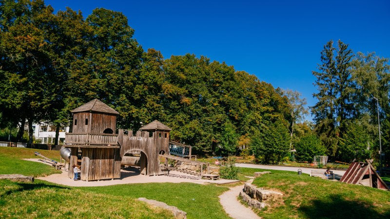 Spielplatz mit Holzkonstruktionen im Stadtpark Welzheim, umgeben von grünen Bäumen und blauem Himmel., © Stuttgart-Marketing GmbH, Thomas Niedermüller Spielplatz mit Holzkonstruktionen im Stadtpark Welzheim, umgeben von grünen Bäumen und blauem Himmel., © Stuttgart-Marketing GmbH, Thomas Niedermüller