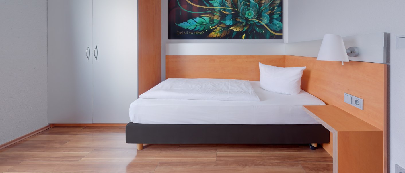 Ein modernes Einzelzimmer mit Holzboden, einem Bett, einem Schrank und einem Kunstwerk an der Wand., © attimo Hotel Stuttgart