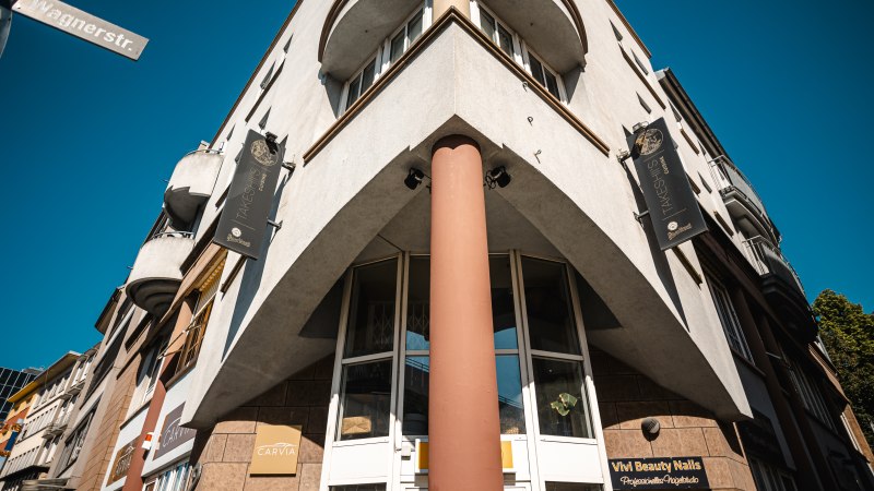 Eckgeb&auml;ude mit Schildern von Takeshiis Lounge und Vivi Beauty Nails, aufgenommen von unten. Stra&szlig;enschild Wagnerstra&szlig;e sichtbar, blauer Himmel im Hintergrund., &copy; SMG Stuttgart Marketing GmbH - Sarah Schmid