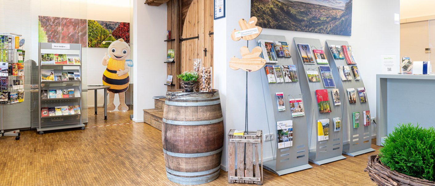Innenansicht einer Tourist-Info mit Prospektständern, einem Weinfass und einer Bienenfigur. Helle, einladende Atmosphäre., © Remstal Tourismus, Peter Schuster