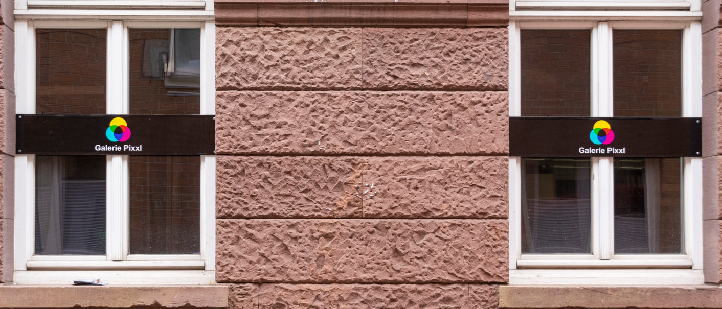 Zwei Fenster mit Schildern der Galerie Pixxl an einer roten Backsteinwand. Die Schilder zeigen ein buntes Logo und den Namen der Galerie., &copy; Stuttgart-Marketing GmbH, Sarah Schmid