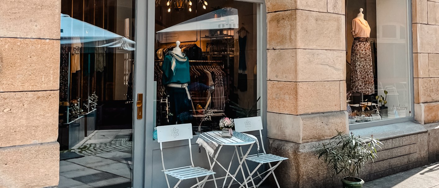 Ein kleines Ladengeschäft mit Schaufenster, dekoriert mit Kleidung. Davor stehen zwei weiße Stühle und ein Tisch auf dem Gehweg., © MAGASIN Geißstrasse 15, Stuttgart Ein kleines Ladengeschäft mit Schaufenster, dekoriert mit Kleidung. Davor stehen zwei weiße Stühle und ein Tisch auf dem Gehweg., © MAGASIN Geißstrasse 15, Stuttgart