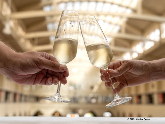Zwei Personen stoßen mit Sektgläsern in einer lichtdurchfluteten Halle an, vermutlich in der Stuttgarter Markthalle., © Stuttgart Marketing GmbH Zwei Personen stoßen mit Sektgläsern in einer lichtdurchfluteten Halle an, vermutlich in der Stuttgarter Markthalle., © Stuttgart Marketing GmbH