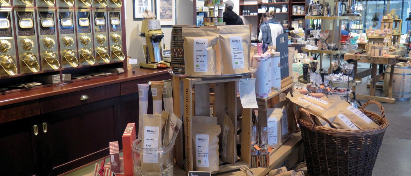 Verkaufsraum einer Kaffeerösterei mit goldenen Kaffeespendern, Kaffeetüten und verschiedenen Produkten auf Holztischen und Regalen., © Stuttgart-Marketing GmbH, Lara Seeger Verkaufsraum einer Kaffeerösterei mit goldenen Kaffeespendern, Kaffeetüten und verschiedenen Produkten auf Holztischen und Regalen., © Stuttgart-Marketing GmbH, Lara Seeger