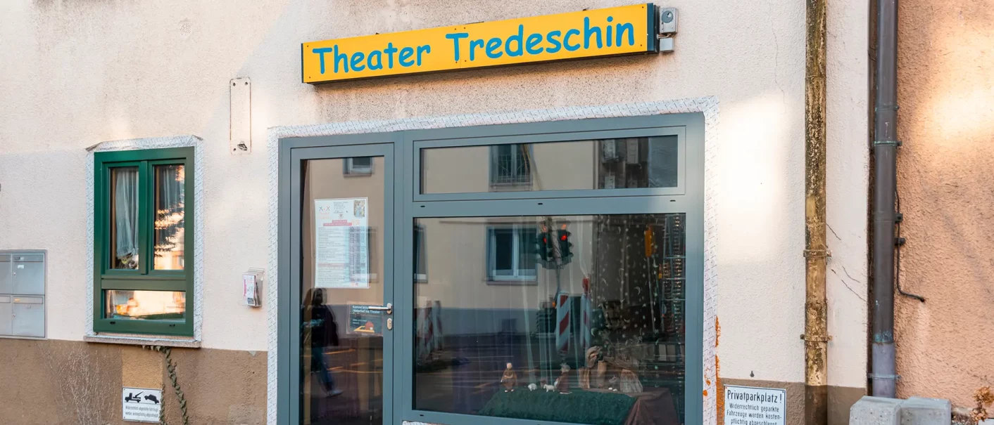 Eingang des Theater Tredeschin mit einem gelben Schild über der Tür. Ein Fenster mit Vorhang und ein kleiner Schaukasten sind sichtbar., © SMG, Sarah Schmid Eingang des Theater Tredeschin mit einem gelben Schild über der Tür. Ein Fenster mit Vorhang und ein kleiner Schaukasten sind sichtbar., © SMG, Sarah Schmid