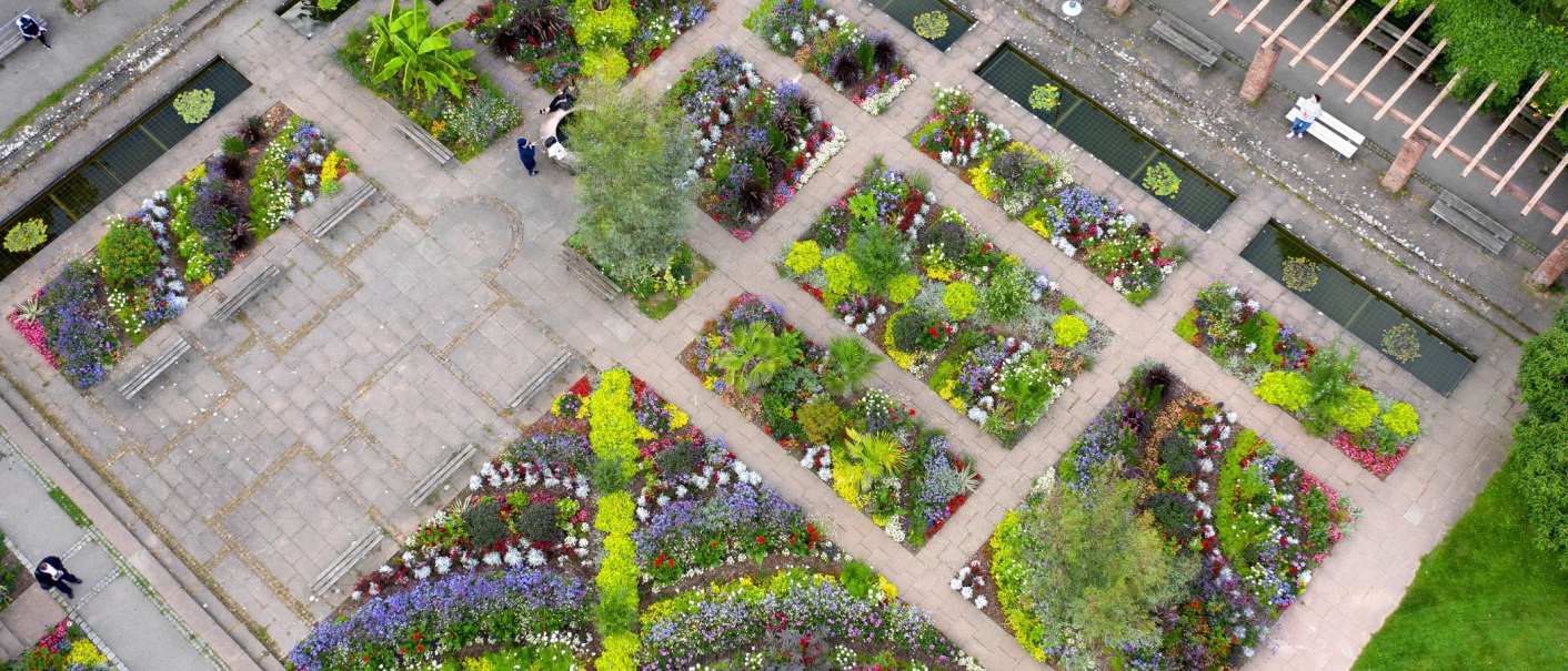 Luftaufnahme eines Gartens mit bunten Blumenbeeten, Gehwegen und Sitzbänken. Menschen spazieren und entspannen sich im Stadtgarten Kornwestheim., © Stadt Kornwestheim Luftaufnahme eines Gartens mit bunten Blumenbeeten, Gehwegen und Sitzbänken. Menschen spazieren und entspannen sich im Stadtgarten Kornwestheim., © Stadt Kornwestheim