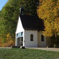 Weiße Kapelle mit Glockenturm, umgeben von herbstlich gefärbten Bäumen und grünem Rasen., © Foto: Cornelia Steinbach Weiße Kapelle mit Glockenturm, umgeben von herbstlich gefärbten Bäumen und grünem Rasen., © Foto: Cornelia Steinbach