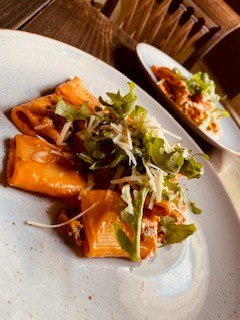 Rigatoni in Tomatensauce mit Rucola und K&auml;se auf einem Teller serviert, im Hintergrund ein weiterer Teller., &copy; Emilio's
