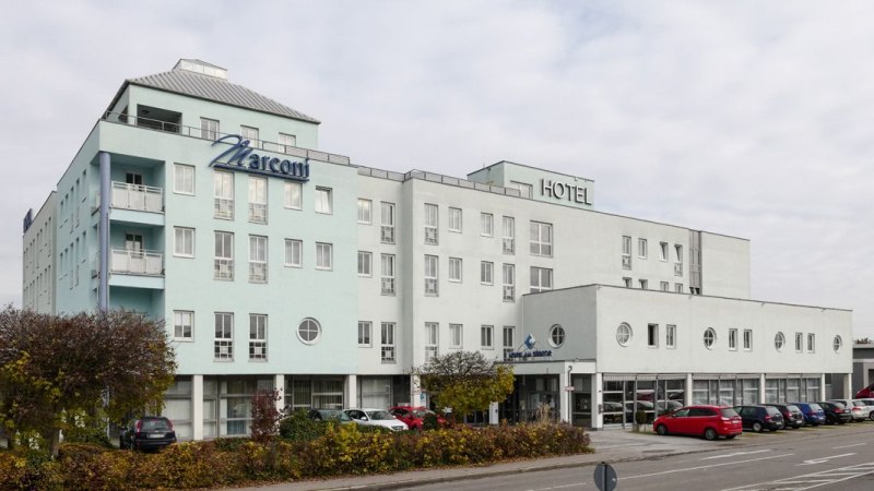 Mehrst&ouml;ckiges Hotel mit dem Namen Marconi, helle Fassade, geparkte Autos und B&auml;ume im Vordergrund., &copy; Hotel S&uuml;dtor