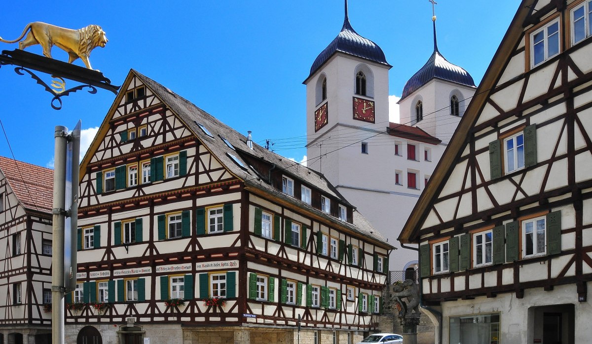 Fachwerkhäuser und Kirchtürme in Wiesensteig, Deutschland, bei sonnigem Wetter. Ein goldener Löwe ziert ein Schild im Vordergrund., © Landkreis Göppingen Fachwerkhäuser und Kirchtürme in Wiesensteig, Deutschland, bei sonnigem Wetter. Ein goldener Löwe ziert ein Schild im Vordergrund., © Landkreis Göppingen