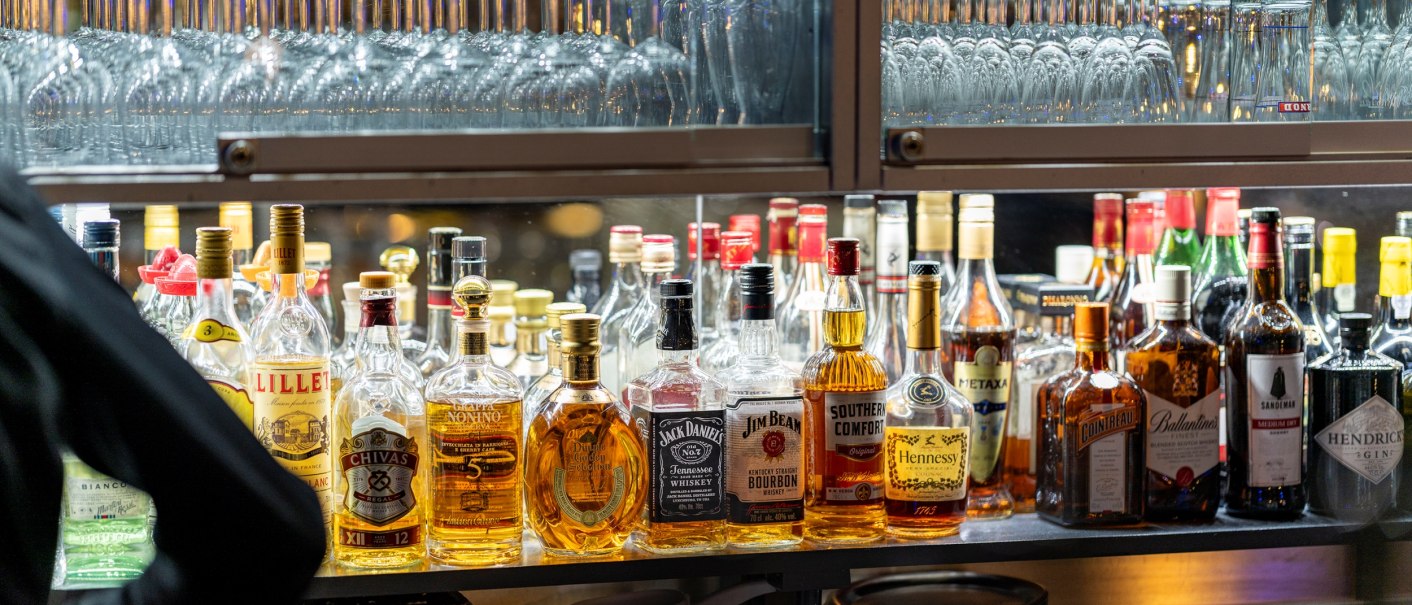 Regal in einer Bar mit einer Vielzahl von Spirituosenflaschen und Gläsern. Verschiedene Marken und Sorten sind sichtbar., © Plaza Residence Stuttgart-Ditzingen Regal in einer Bar mit einer Vielzahl von Spirituosenflaschen und Gläsern. Verschiedene Marken und Sorten sind sichtbar., © Plaza Residence Stuttgart-Ditzingen
