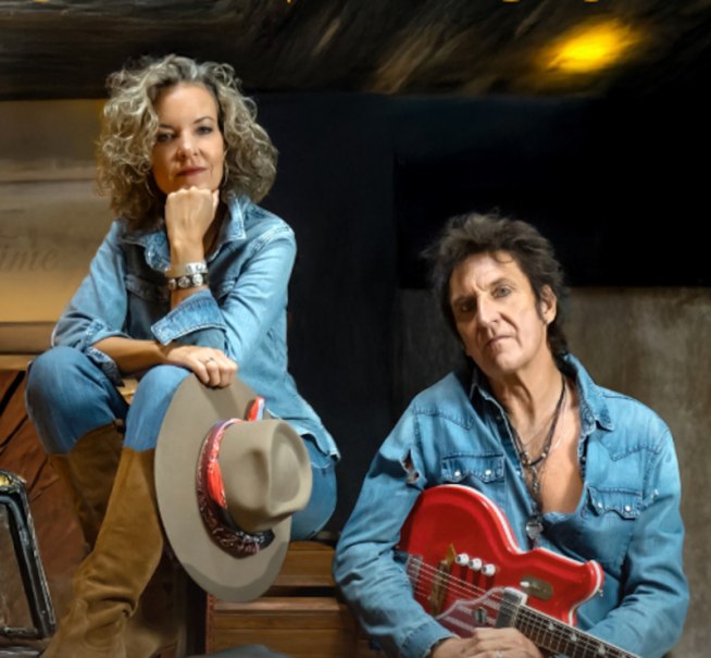 Zwei Personen in Jeanskleidung, die Frau sitzt mit einem Hut auf dem Knie, der Mann h&auml;lt eine rote E-Gitarre. Beide blicken in die Kamera., &copy; Scala Kultur Live gGmbH