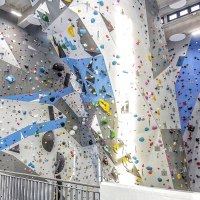 Kletterhalle mit hohen, bunten Wänden und Griffen. Im Vordergrund ein Sitzbereich mit orangen Kissen und Sesseln., © Griffwerk Ludwigsburg Kletterhalle mit hohen, bunten Wänden und Griffen. Im Vordergrund ein Sitzbereich mit orangen Kissen und Sesseln., © Griffwerk Ludwigsburg