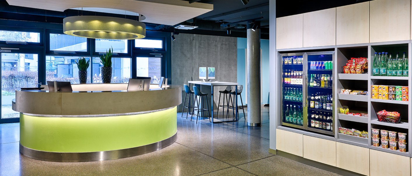 Moderne Rezeption mit beleuchtetem Tresen, Snack- und Getr&auml;nkebereich. Helle, einladende Atmosph&auml;re mit Pflanzen und Sitzgelegenheiten., &copy; Aloft Stuttgart