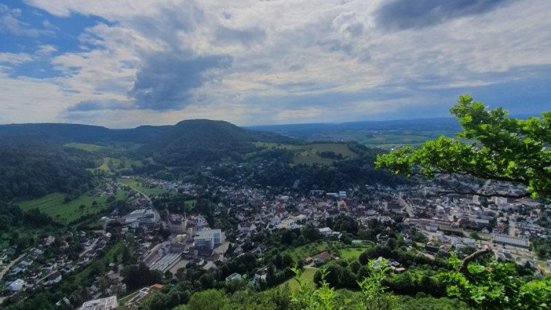 Panoramablick auf Heubach, umgeben von gr&uuml;nen H&uuml;geln und W&auml;ldern unter einem bew&ouml;lkten Himmel mit Sonnenstrahlen., &copy; Foto: Shari Dawids