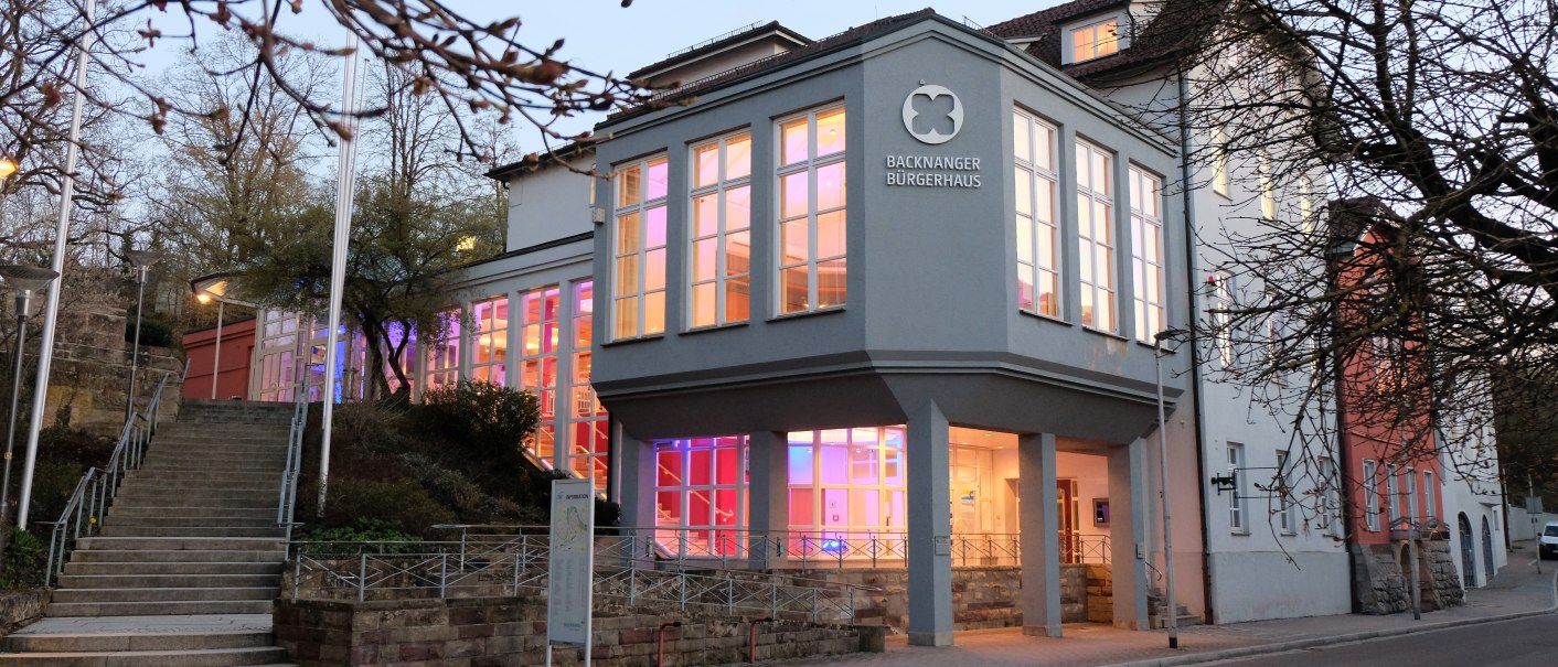 Das Backnanger Bürgerhaus bei Dämmerung, mit beleuchteten Fenstern und kahlen Bäumen im Vordergrund. Eine Treppe führt zum Eingang., © Kultur-und Sportamt Backnang Das Backnanger Bürgerhaus bei Dämmerung, mit beleuchteten Fenstern und kahlen Bäumen im Vordergrund. Eine Treppe führt zum Eingang., © Kultur-und Sportamt Backnang