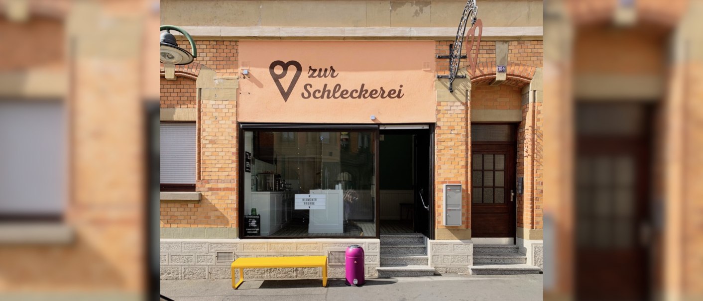 Gebäude mit der Aufschrift 'zur Schleckerei', gelbe Bank und lila Mülleimer davor., © Zur Schleckerei