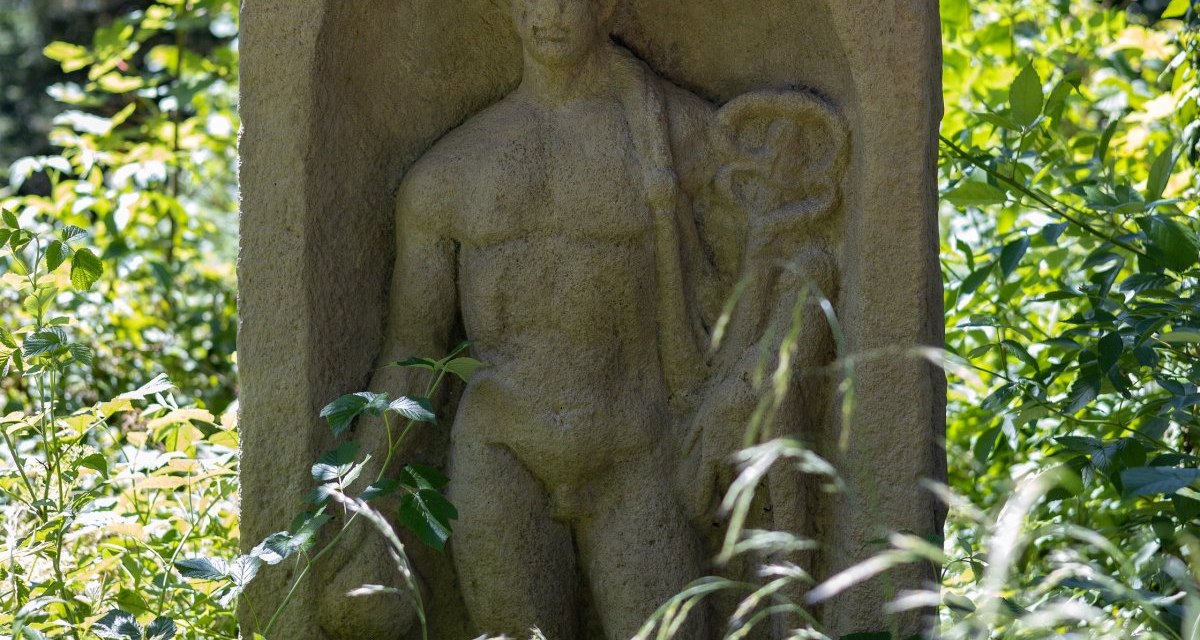 Ein Steinrelief zeigt eine männliche Figur, umgeben von üppigem Grün im Rotenbachtal., © Foto Thomas Zehnder Ein Steinrelief zeigt eine männliche Figur, umgeben von üppigem Grün im Rotenbachtal., © Foto Thomas Zehnder
