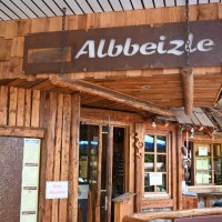 Rustikales Gebäude mit Holzverkleidung und dem Schild 'Albbeizle'. Der Eingang ist mit Holzdekor und Schildern gestaltet.
