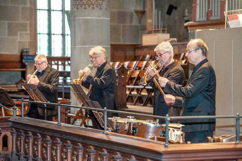 Vier Musiker in einer Kirche spielen Trompeten und Pauken. Sie tragen schwarze Anzüge und stehen vor Notenständern. Im Hintergrund sind Kirchenbänke zu sehen., © Konzertbüro Joachim Jung Vier Musiker in einer Kirche spielen Trompeten und Pauken. Sie tragen schwarze Anzüge und stehen vor Notenständern. Im Hintergrund sind Kirchenbänke zu sehen., © Konzertbüro Joachim Jung