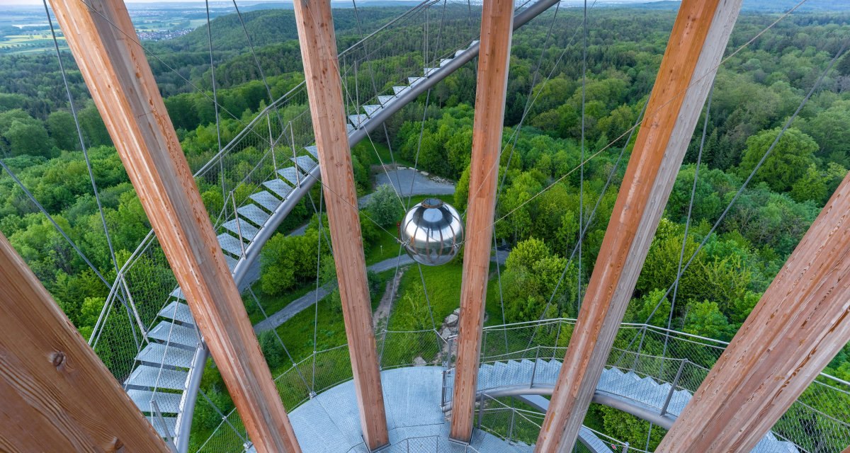 Blick vom Sch&ouml;nbuchturm auf eine spiralf&ouml;rmige Treppe und dichte gr&uuml;ne W&auml;lder. Eine silberne Kugel h&auml;ngt zwischen den Holzs&auml;ulen., &copy; Stuttgart Marketing GmbH Martina Denker