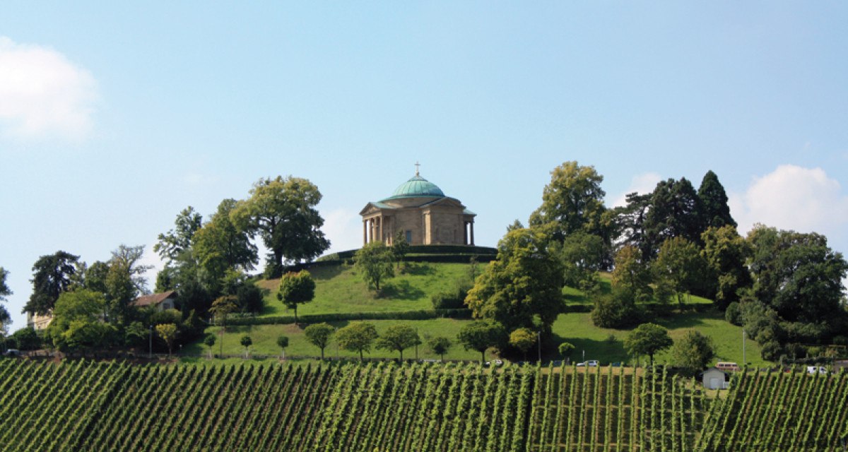 Die Grabkapelle auf dem Württemberg thront auf einem Hügel, umgeben von grünen Weinbergen und Bäumen unter einem blauen Himmel., © Stuttgart-Marketing GmbH Die Grabkapelle auf dem Württemberg thront auf einem Hügel, umgeben von grünen Weinbergen und Bäumen unter einem blauen Himmel., © Stuttgart-Marketing GmbH