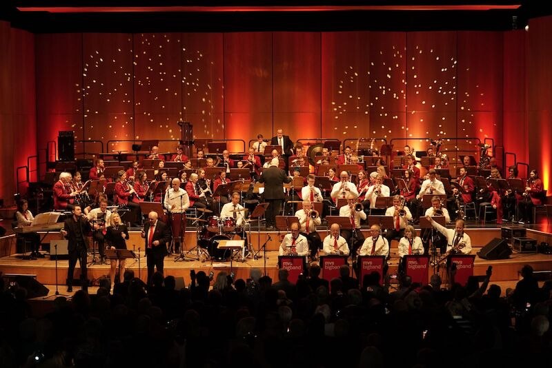 Ein Orchester spielt auf einer Bühne, umgeben von rotem Licht. Musiker in weißen Hemden und roten Westen. Publikum im Vordergrund., © Stadt Sindelfingen Ein Orchester spielt auf einer Bühne, umgeben von rotem Licht. Musiker in weißen Hemden und roten Westen. Publikum im Vordergrund., © Stadt Sindelfingen
