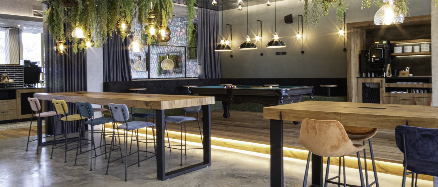 Moderne Lounge mit Billardtisch, hohen Tischen und bunten Stühlen, dekoriert mit hängenden Pflanzen und stilvollen Lampen., © 13 6 Design GmbH (Judenhof 10, 89073 Ulm)