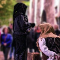 Mittelalterliche Szene mit zwei Personen in historischer Kleidung, eine kniet vor einem Holzblock, während die andere daneben steht. Zuschauer im Hintergrund., © Esslinger Stadtmarketing &amp; Tourismus GmbH