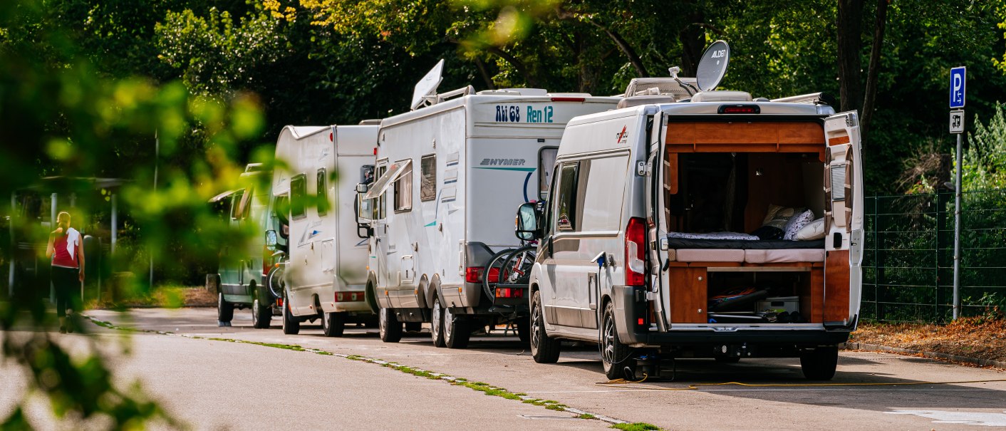 Mehrere Wohnmobile parken auf einem Stellplatz, umgeben von Bäumen. Eine Person geht in der Nähe vorbei., © Stuttgart-Marketing GmbH, Thomas Niedermüller