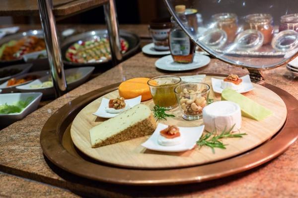 Verschiedene Käsesorten, Nüsse und Marmelade auf einem Holzteller, Teil eines Frühstücksbuffets., © Kronen Hotel GmbH