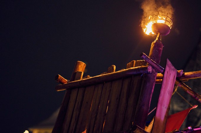 Eine mittelalterliche Holzplattform mit einer brennenden Fackel, die den Nachthimmel erleuchtet. Im Hintergrund sind Lichter zu sehen., © Esslinger Stadtmarketing &amp; Tourismus GmbH